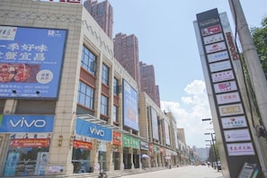 A street with commercial buildings, including a Vivo store and a signboard with various advertisements. - Hongye Business Hotel (Yichang)