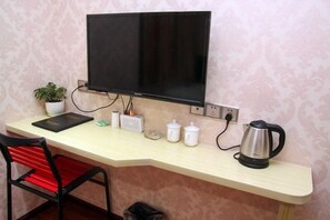 A room with a desk, a chair, a television, a kettle, and a potted plant. - Hongye Business Hotel (Yichang)