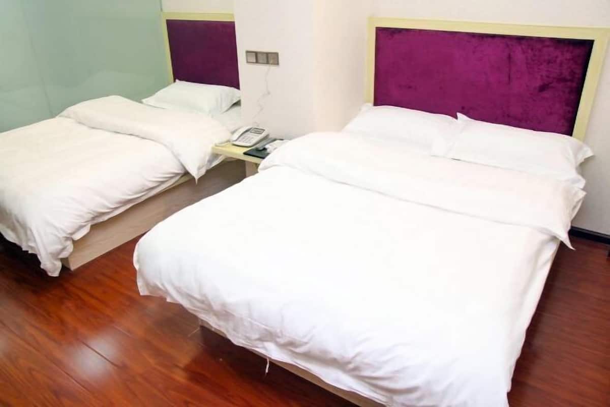Habitación de hotel con dos camas, una mesita de noche con teléfono y un cabecero morado.