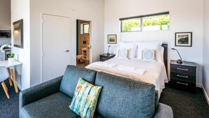Un dormitorio con cama, sofá, mesita de noche y ventana.