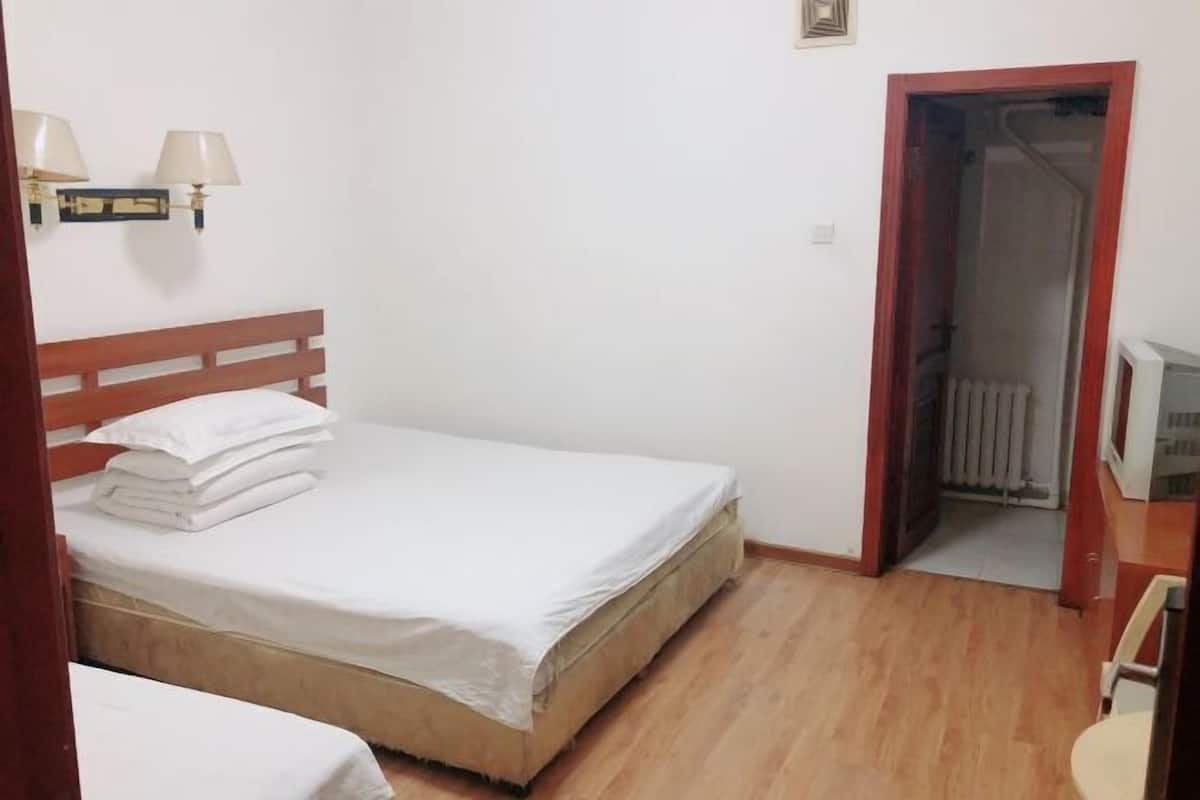Ein Schlafzimmer mit einem Bett, einem Nachttisch, einer Lampe und einer Tür zu einem Badezimmer.