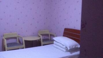 Una habitación pequeña con una cama, dos sillas y una mesita.