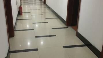 A corridor with a tiled floor and wooden doors.