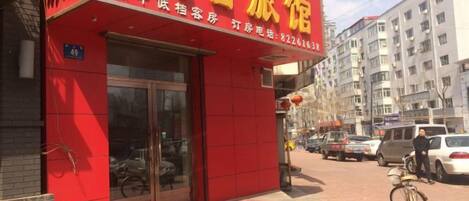 A red building with a sign that reads 'Xia Jiang Travel Hotel.'