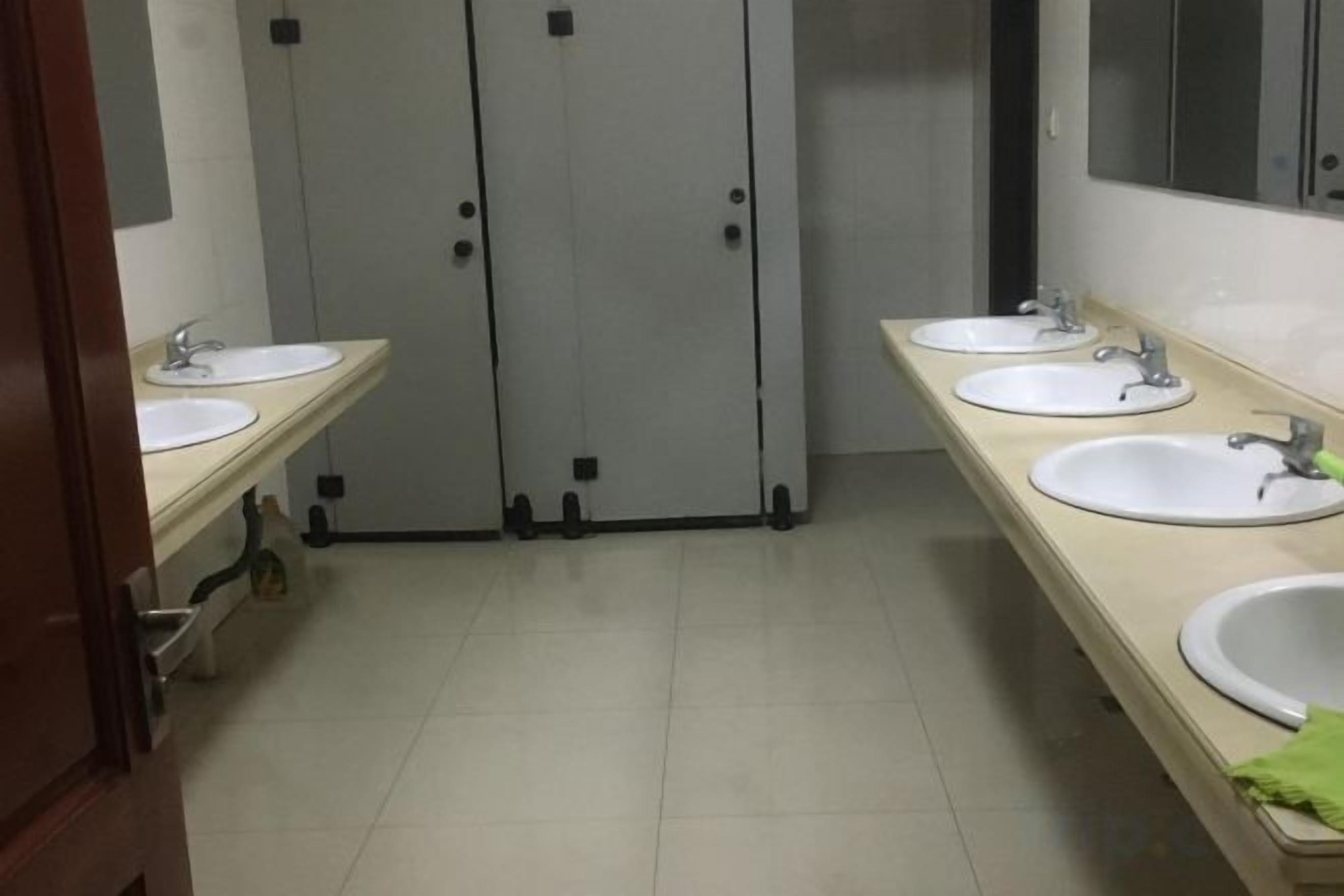 A restroom with three sinks, two toilets, and a mirror.