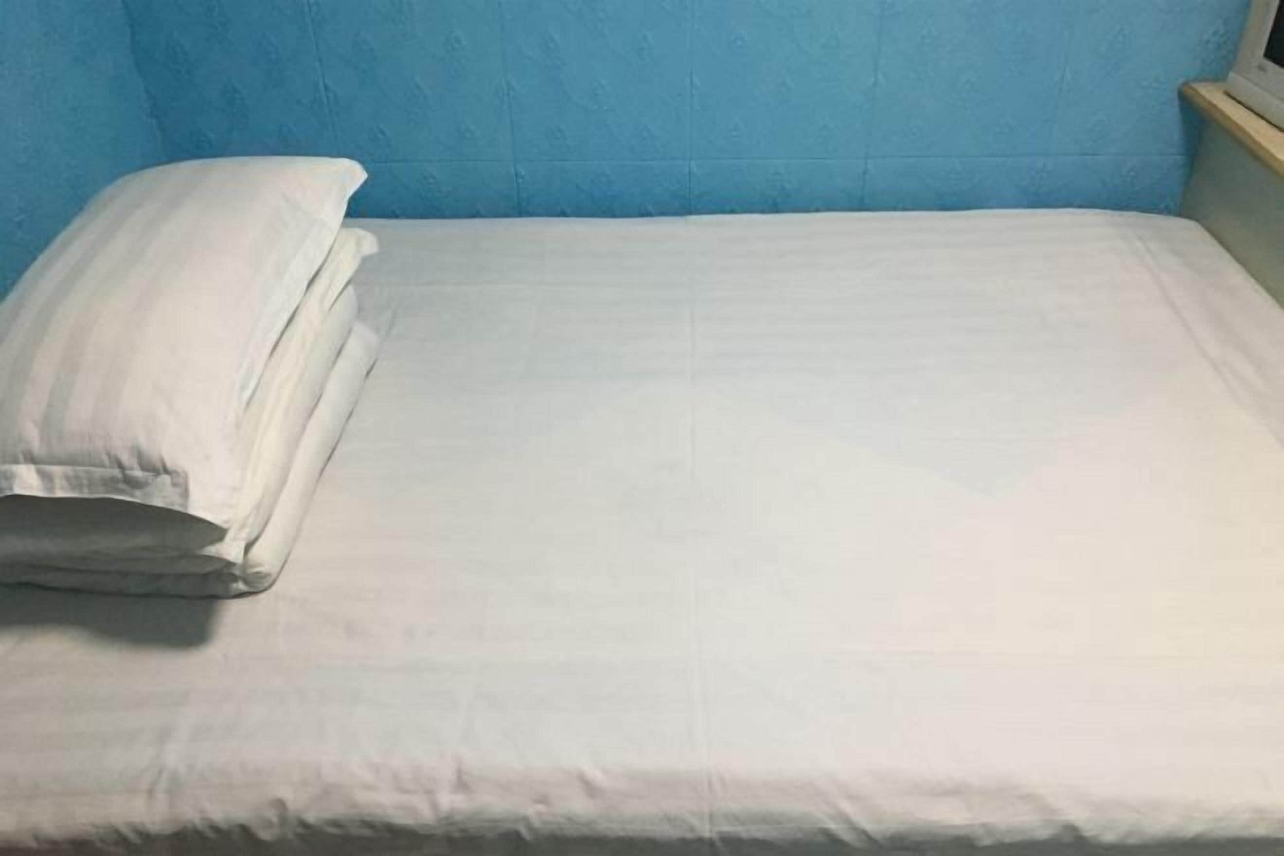 A bed with white bedding in a room with blue walls.