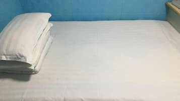 Una cama con ropa de cama blanca en una habitación con paredes azules.