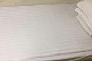 A bed with a white sheet and a neatly folded blanket on the right side. - Harbin Summer Hotel (Harbin)