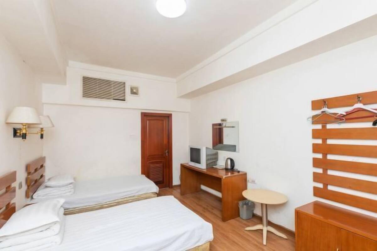 Ein Hotelzimmer mit zwei Betten, einem Schreibtisch mit Computer, einem kleinen Tisch und einem Kleiderschrank.