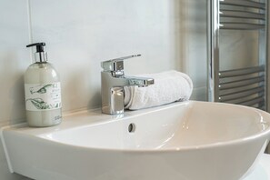 A bathroom sink with a bottle of lotion and a towel. - 3 Bedroom, 3.5 Bathroom House, Goodwood, Chichester (Chichester)