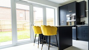 A modern kitchen with dark cabinets, a built-in oven, and a large window. - 3 Bedroom, 3.5 Bathroom House, Goodwood, Chichester (Chichester)