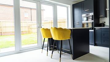 A modern kitchen with dark cabinets, a built-in oven, and a large window.