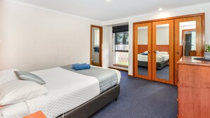 Une chambre à coucher comprenant un lit, une commode et une porte coulissante donnant sur un balcon.