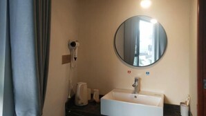 A bathroom with a round mirror, a sink, a hairdryer, and a towel rack. - yi xian hong cun Yue han bo Inn (Yi County)