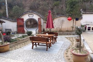 An outdoor seating area with tables and benches, surrounded by potted plants and a decorative archway. - yi xian hong cun Yue han bo Inn (Yi County)
