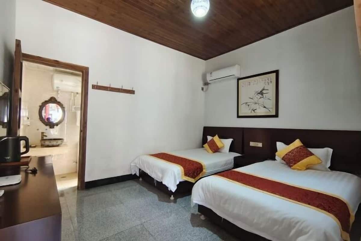 Habitación de hotel con dos camas, techo de madera, una obra de arte enmarcada en la pared y un escritorio con cafetera.