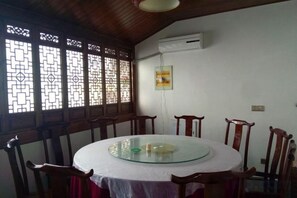A dining area with a round glass table, wooden chairs, and decorative window screens. - yi xian hong cun Yue han bo Inn (Yi County)