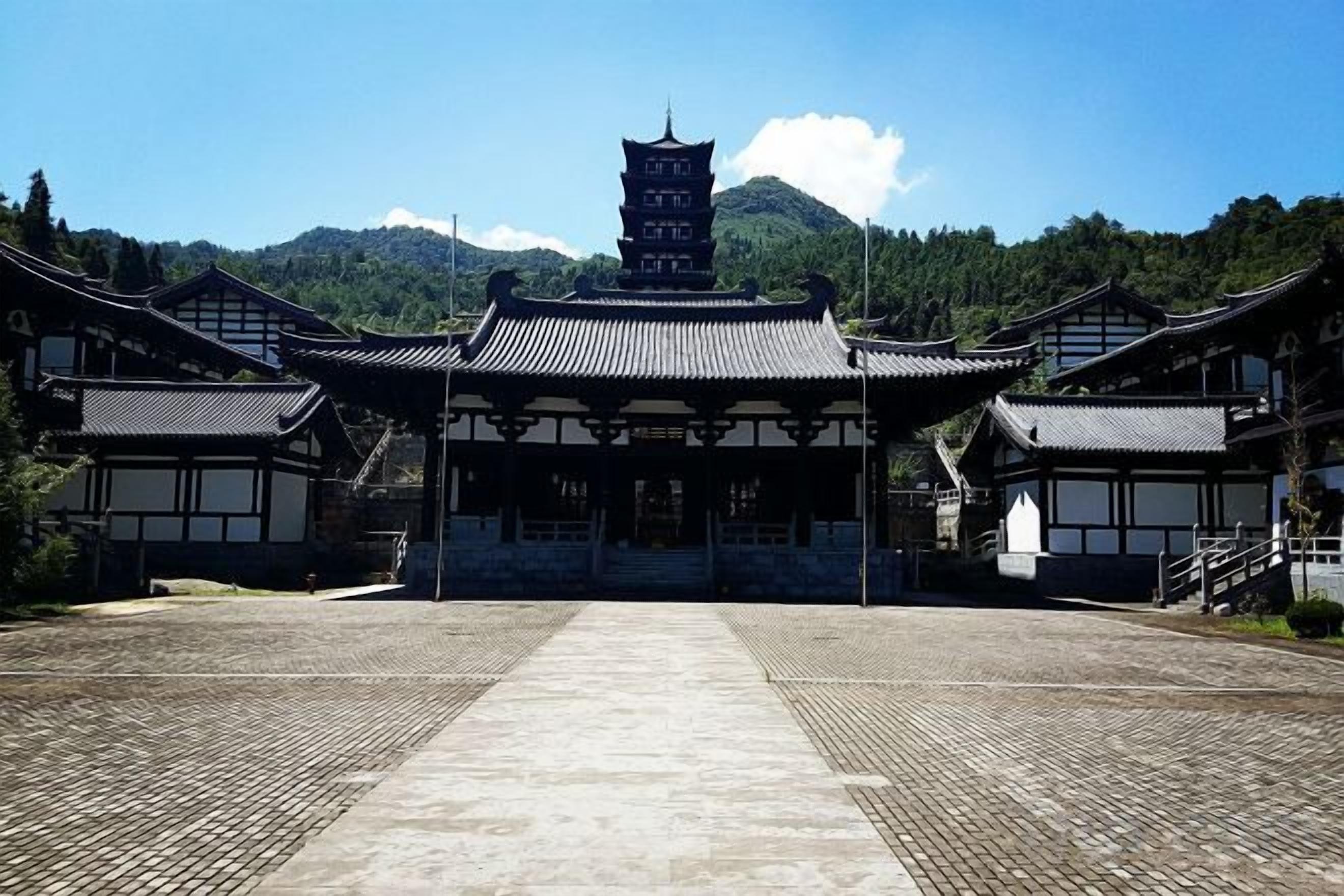 Ein traditionelles japanisches Gebäude mit einem zentralen Turm, einem mit Fliesen belegten Innenhof und einer bergigen Kulisse.