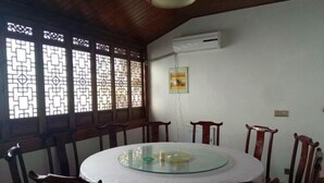 A dining area with a round glass table, wooden chairs, and a decorative window with intricate patterns. - yi xian hong cun Yue han bo Inn (Yi County)