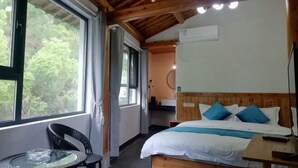 A room with a bed, a table, and a chair. There is a window with a view of trees. - yi xian hong cun Yue han bo Inn (Yi County)