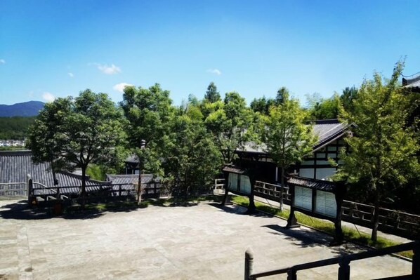 Un bâtiment japonais traditionnel, avec un toit recouvert de tuiles, entouré d’arbres et sous un ciel dégagé.