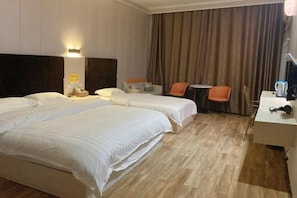 A hotel room with two beds, a desk, a chair, and a small table. - Libo Jiaxin Hotel (Libo)