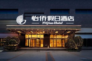 A hotel entrance with a modern facade, large glass doors, and a prominent logo.