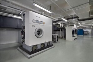 A large industrial machine in a clean, well-lit room with a flat floor and visible pipes on the ceiling.