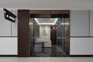 A reception area with a glass partition, a reception desk, and a vertical wooden panel.