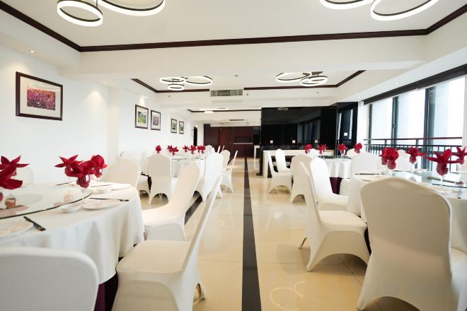 A banquet hall with rows of tables and chairs, large windows, and a central aisle.