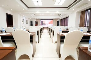 A conference room with rows of tables and chairs, equipped with water bottles, and a view of the outside through large windows. - Yi Qiao Hotel (Chengdu)
