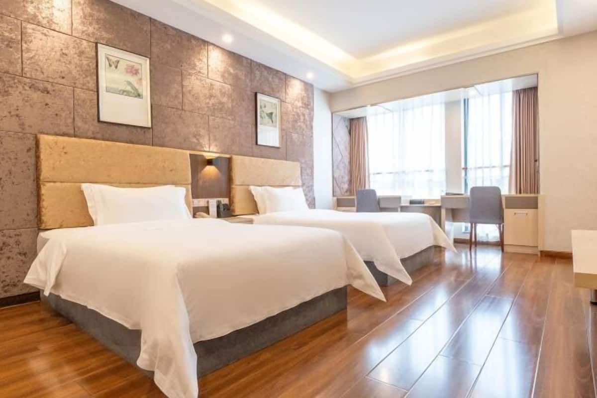 A hotel room with two beds, a desk, and a chair.