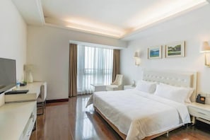 A hotel room with a large bed, a desk, a chair, a TV, and a window with curtains. - Yi Qiao Hotel (Chengdu)