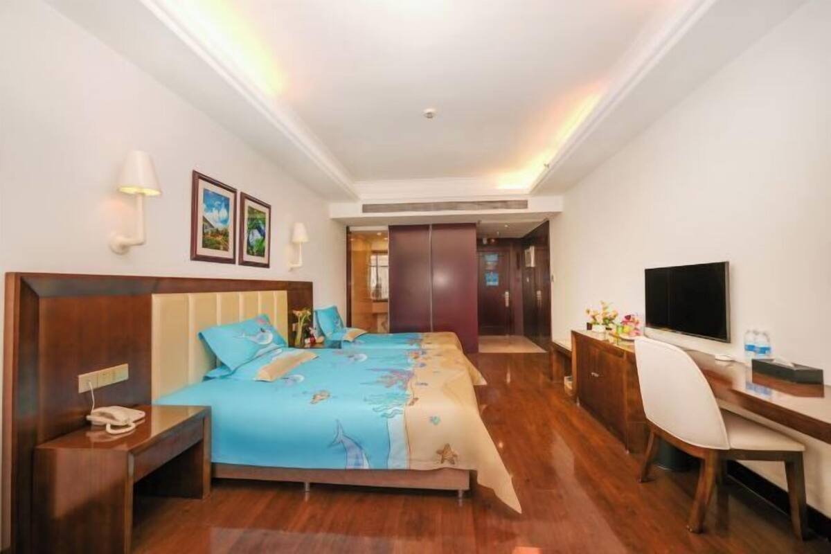 A hotel room with a bed, desk, chair, TV, and a wardrobe.