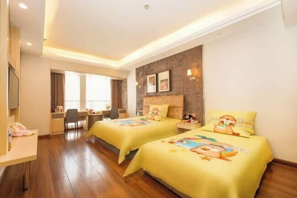 A hotel room with two beds, a desk, a chair, and a TV.