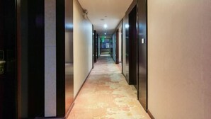 A hotel hallway with a carpeted floor, doors on both sides, and a light fixture on the ceiling. - Teng Chuan Hotel (Lichuan)