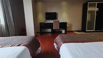 A hotel room with two beds, a desk with a TV, and a wardrobe.