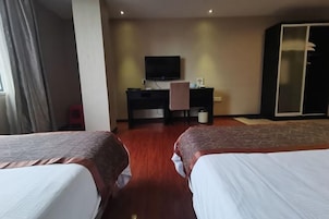 A hotel room with two beds, a desk with a TV, and a wardrobe.