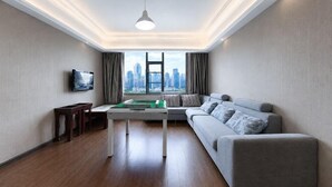 A modern living room with a sofa, a coffee table, a TV, and a city view through large windows. - Teng Chuan Hotel (Lichuan)