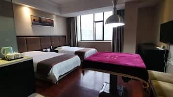 A hotel room with two beds, a desk with a lamp, a TV, and a window with curtains.