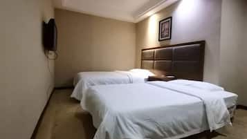 A hotel room with two beds, a headboard, a wall-mounted TV, and a framed picture.