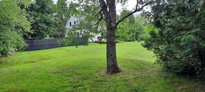 Enjoy the serene atmosphere of this beautifully landscaped yard with a lush lawn, mature tree, and wooden fence.