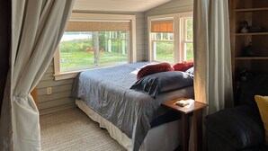 Een slaapkamer met een bed, nachtkastje en een raam met gordijnen.