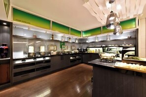 A modern kitchen with stainless steel appliances, wooden cabinets, and a central island with food displays.