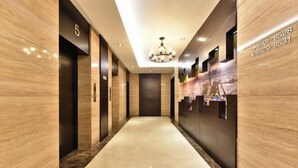 A modern hotel lobby with a marble floor, a chandelier, and a reception desk. - Orange Hotel Select (Beijing Yizhuang Wanyuan Street) (Beijing)