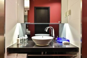 Un baño moderno con un espejo grande, un lavabo blanco y una encimera negra.