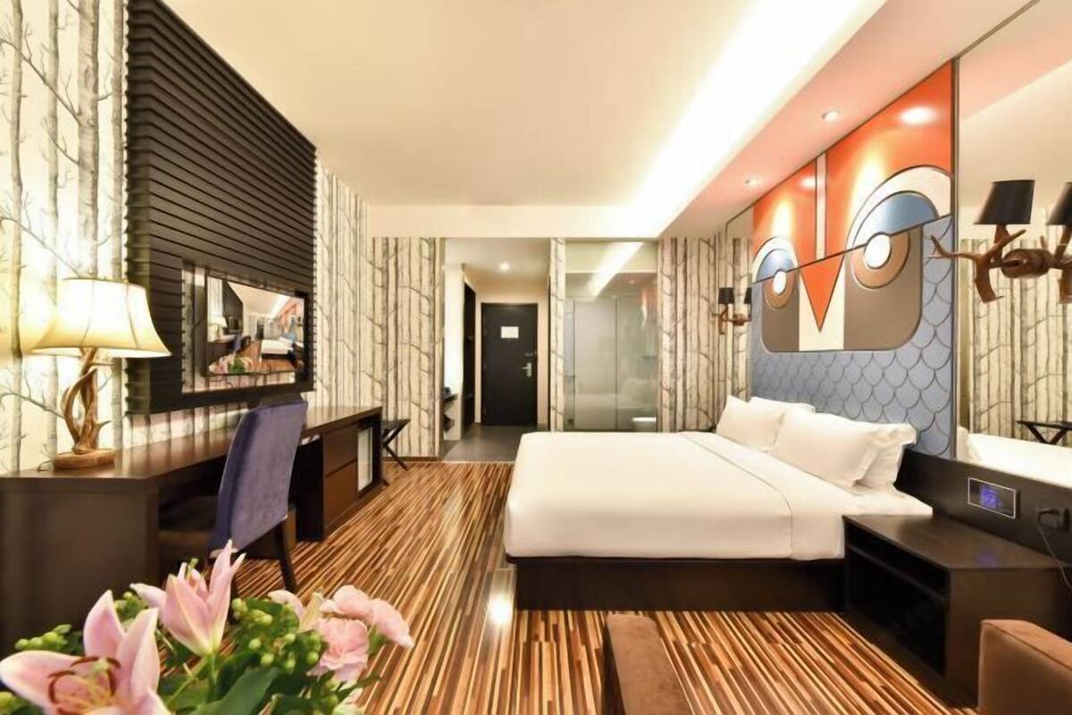 A modern hotel room with a large bed, a desk, and a mirror.