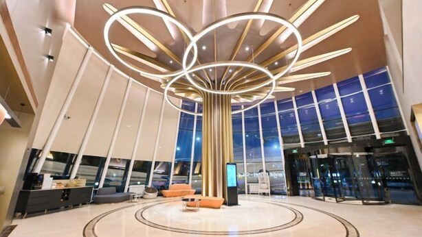 A modern lobby with a circular seating area, a large digital screen, and a unique ceiling design. - Orange Hotel Select (Beijing Yizhuang Wanyuan Street) (Beijing)