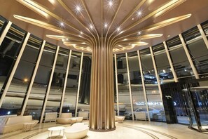 A modern lobby with a central column, seating areas, and large windows. - Orange Hotel Select (Beijing Yizhuang Wanyuan Street) (Beijing)