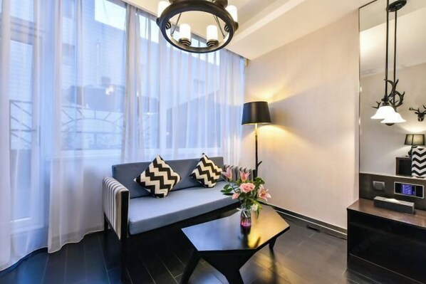 Una sala moderna con un sofá, una mesita auxiliar con un florero, una lámpara y un espejo con objetos decorativos.